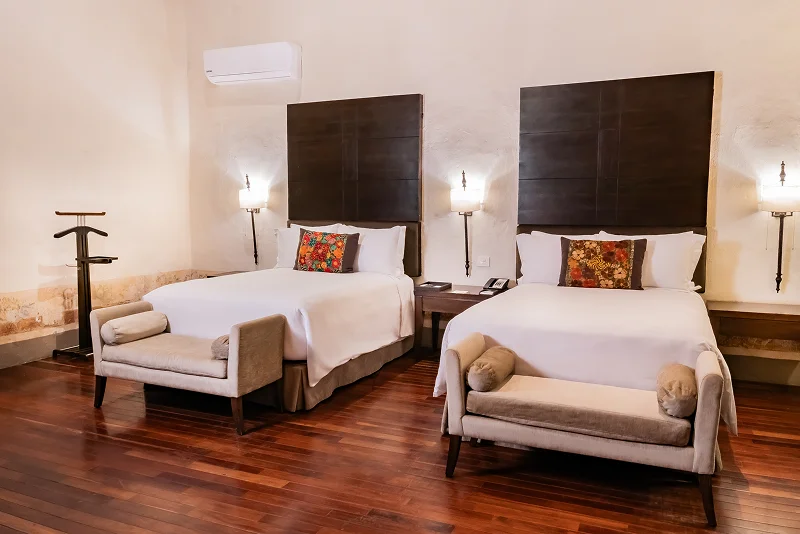 Dos camas matrimoniales en habitación de hotel colonial